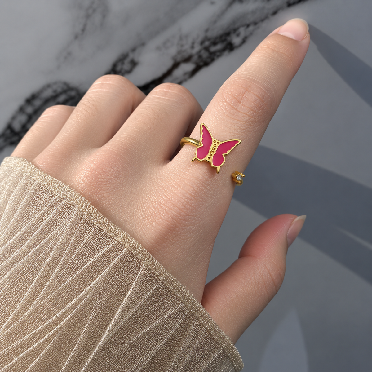 Bague anti-stress rotative Papillon Robuste dorée, papillon aux ailes en émail rose fuchsia, portée au doigt