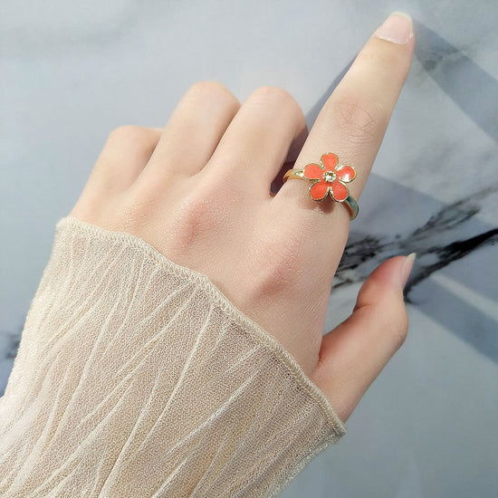 Bague anti-stress rotative Fleur Design couleur orange portée au doigt