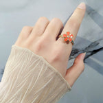 Bague anti-stress rotative Fleur Design couleur orange portée au doigt